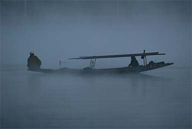 A fisherman rows his boat in the waters of Dal Lake in Srinagar
