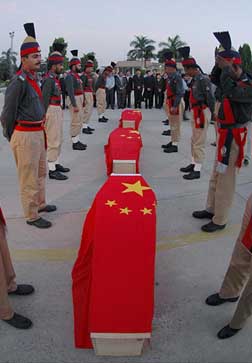 Pakistani and Chinese Embassy officials stand near coffins of three Chinese technicians at Faisal air base in Karachi