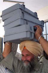 An election official carries Electronic Voting Machines for the final phase of Lok Sabha elections in Patiala 