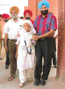 Ninetyeight-year-old Dhian Kaur being helped by her grandson Jaspal Bhatti to cast her vote 