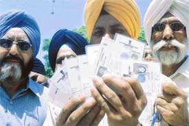 Disappointed voters show their voters cards after they could not find their names in the voter list at Thrike village