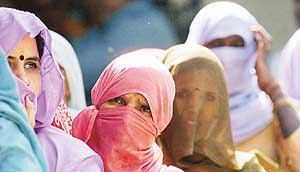 Women with their faces covered stand in Queue at a polling station of Outer Delhi constituency during the final phase of the Lok Sabha elections on Monday. 