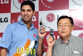 Managing Director of LG Electronics K. R. Kim (right) poses with new mobile phones, along with Indian cricketer Yuvraj Singh