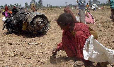 A large portion of the Jaguar engine lies unattended as a woman hunts for scrap pieces on Saturday at the site where the figthter plane