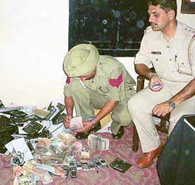 Police personnel count money and inspect other goods seized from a gang running a satta racket from Zirakpur in Dera Bassi