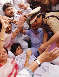 A woman police officer tries to snatch razor blades from Congress activists who threathened to kill themselves during a demonstration outside their party President Sonia Gandhis residence in New Delhi on Tuesday, demanding that she stuck to her decision to become the Prime Minister.