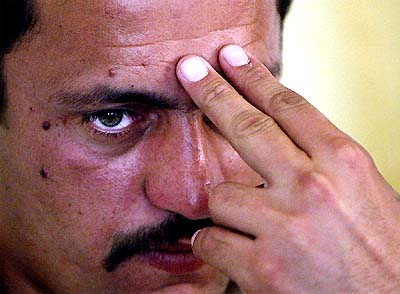 Saddam Saleh, a former prisoner in Abu Ghraib prison, shows how US soldiers pointed their rifles at his head, during an interview with Reuters