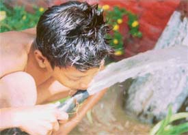 As the mercury soars a boy quenches thirst from a garden hose