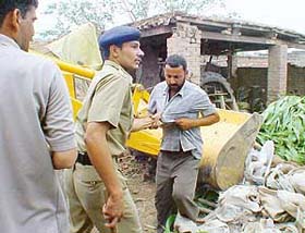 A police personnel drags a sawmill owner after he protested against the demolition drive carried out by the UT Administration at Kajheri village in Chandigarh