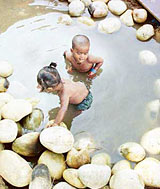 Children enjoy a cool dip in a roadside pond in Patiala on Friday.
