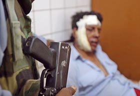 An Iraqi security officer stands near his wounded colleague