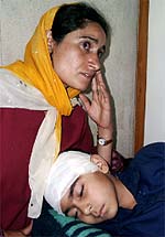A woman attends to her son, who was among the seven schoolchildren and three others injured in a grenade attack by militants at Frisal village in Anantnag district of south Kashmir on Tuesday. 