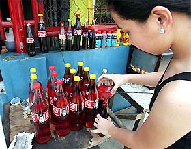 A vendor sells petrol in old soft drink bottles in Manila 