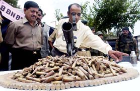 A Border Security Force (BSF) officer points towards a hand grenade and arms and ammunition seized from a militant hide-out in Srinagar on Saturday.