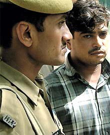 A policeman escorts a member of the Kishan Pehalwan gang, who was arrested by the Delhi Police Special Cell in the Capital