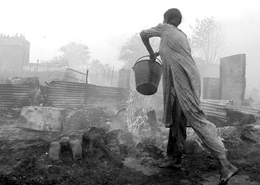 A jhuggi dweller tries to douse the fire that raged in Yamuna Pushta on Tuesday. 