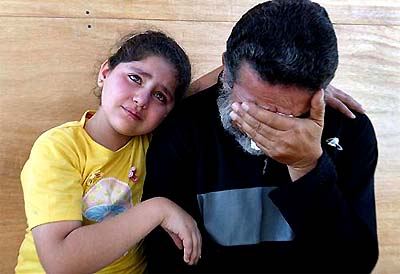An Iraqi detainee breaks down in tears while posing with his daughter for a military photographer during an hour of family visitation inside the Abu Ghraib prison on the outskirts of Baghdad on Wednesday