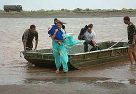 A woman with her child steps out of an Army boat to reach her house in Lassian Enclave across the Ravi and the Ujh