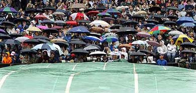 Tennis fans take shelter under their umbrellas