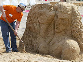 A sculptor gives finishing touches to his sand sculpture