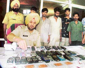 A police official displays mobile phones recovered from a gang of thieves  in Ludhiana