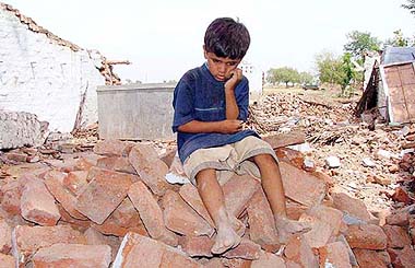 A child sits atop his demolished house as his family prepare to move out of Harsud town on Monday