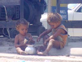 Two children seem to telling each other as they play with the utensils in Ludhiana