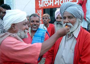 Porters offer sweets to each other to celebrate Railway Budget's declaration of free railway pass to their wives