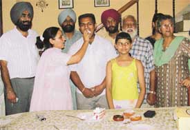 Rampy being offered cake by his mother as relatives look on in their house in Block-G, Bhai Randhir Singh Nagar
