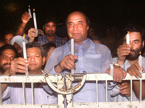 Indian and Pakistani leaders hold candles at the gate on the Indian side of the border at Wagah on Saturday night.