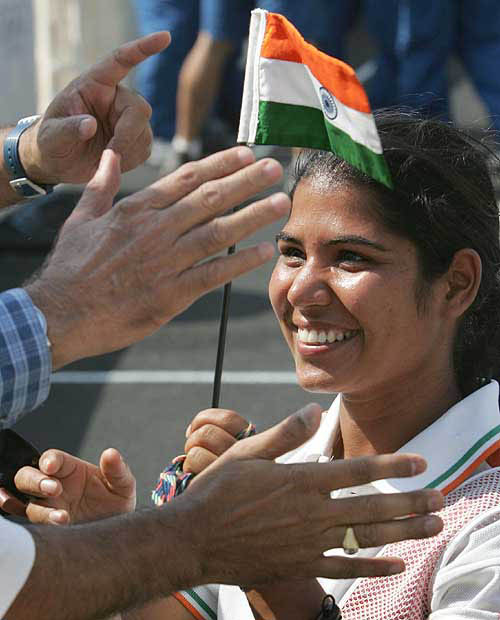 Indian archer Sumangala Sharma, competing in the women's individual archery at the Athens 2004 Olympic Games, holds her national flag, as she is applauded by fans in Athens August 15, 2004. REUTERS/Max Rossi