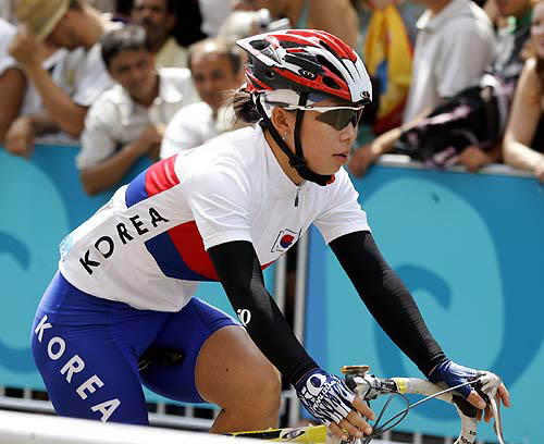 Songhee Han of Korea rides to the starting line of the women's cycling road race in Athens on Sunday. Some 67 competitors take part in the race