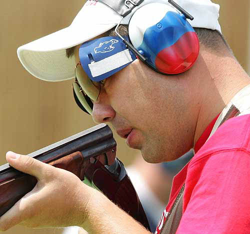 Russia's Alexei Alipov blows through the barrel of his gun during the men's trap final in Athens, August 15, 2004. Alipov took gold with a score of 149. REUTERS/Guang Niu