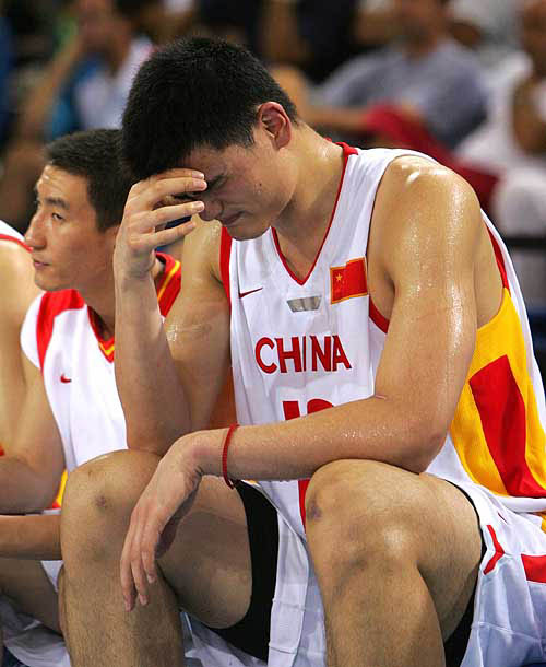 China's Yao Ming sits dejectedly on the bench with team mates after he had been fouled out of their preliminary Group A Olympic basketball game against Spain at the Helliniko Indoor Arena in Athens, August 15, 2004. Spain won the game 83-58. REUTERS/Lucy Nicholson