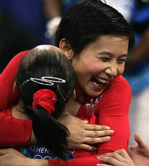 China's Lin Li (R) hugs a team mate during the women's artistic gymnastics qualifying session at the Athens 2004 Olympic Games August 15, 2004. REUTERS/Dylan Martinez