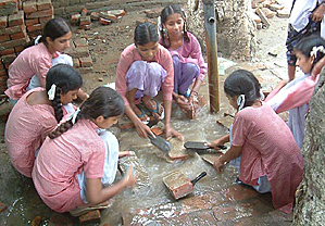 Students of Government Girls Elementary School, Jagdev Kalan village, near Amritsar, clean old bricks to construct a portion of the school building on Friday.
