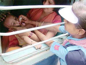 A volunteer administers polio drops to a child inside a train at Mathura railway station 