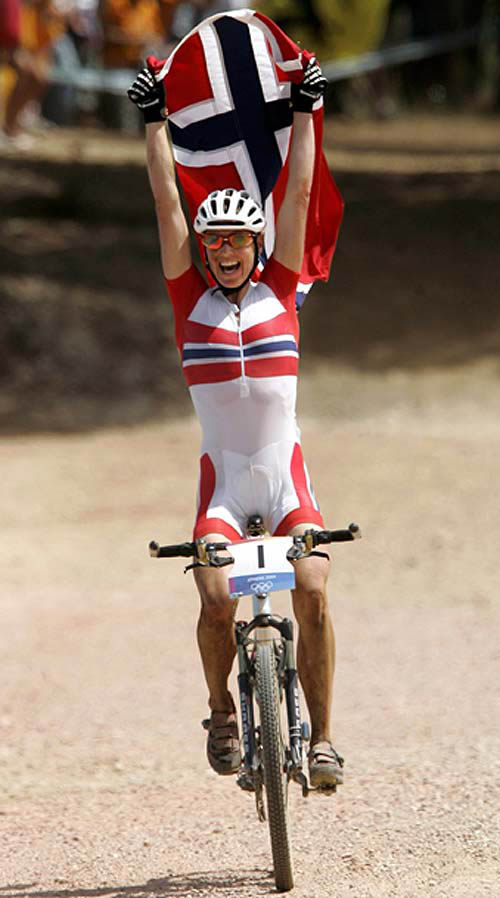 Norway's Gunn-Rita Dahle holds up a Norwegian flag as she crosses the finish line to win gold in the woman's Olympic mountain bike cross country race at the Athens 2004 Olympic Games on August 27. Canada's Marie-Helene Premont won silver and Germany's Sabine Spitz won bronze.