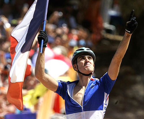 France's Julien Absalon carries a flag before crossing the finish line to win gold in the the men's mountain bike cross country race at the Athens 2004 Olympic Games on August 28