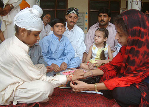 An Indian sister tying rakhi to a Pakistani Sikh boy