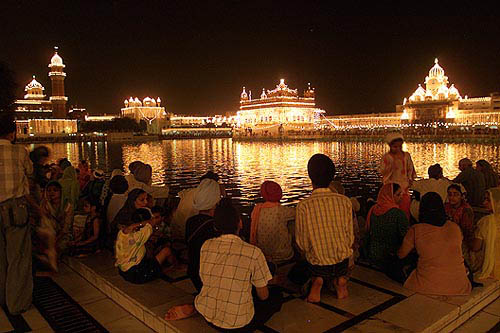 Sikh devotees watch an illuminated Golden Temple