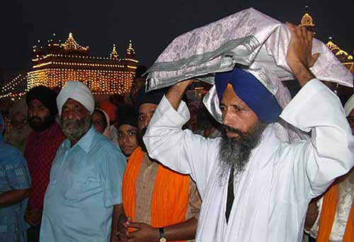 A granthi carries the holy bir of Guru Granth Sahib