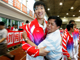 China's 110m hurdles Olympic gold medallist Liu Xiang hugs his school teacher during a welcoming ceremony upon his arrival at his athletic school in Shanghai