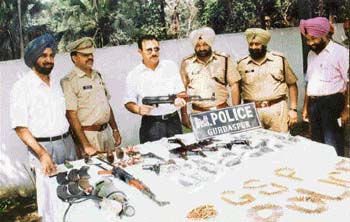 The IG, Jalandhar Zone, Mr S.K. Sharma, holding an AK-56 rifle, the DIG, Border Range, Mr Paramjit Singh Gill, extreme left, and the SSP, Gurdaspur, Mr Narinder Bhargav, at a press conference in Gurdaspur on Sunday, along with seized arms, explosives and ammunition.
