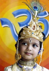 A boy dressed as Lord Krishna performs at a function on the eve of Janamashthami 