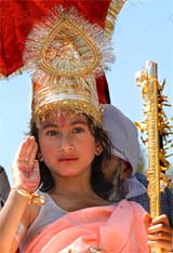 A girl dressed as Lord Krishna takes part in a procession on the occasion of Janmashtami