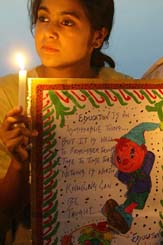 A girl holds a candle and a placard during a procession organised by the Rotary Club of Kashmir on the occasion of World Literacy Day