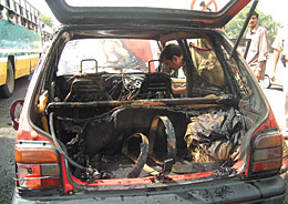 A police officer inspecting the Maruti car which caught fire after an LPG cylinder burst at ITO Chowk in the Capital.