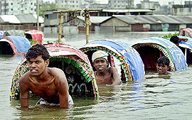 Rickshaw-pullers wade through a flooded street