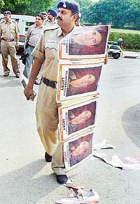 Police personnel remove posters from the Panjab University campus in Chandigarh